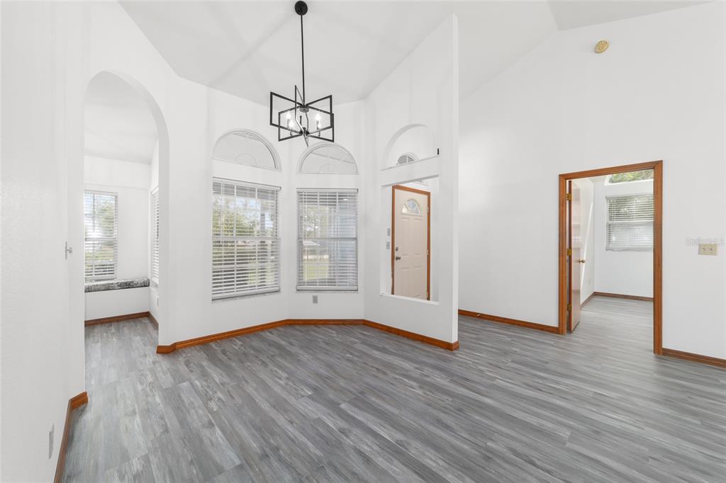A bright room with vaulted ceilings, gray wood-look flooring, and a modern black chandelier — 13984 SW 80TH STREET, DUNNELLON, FL
