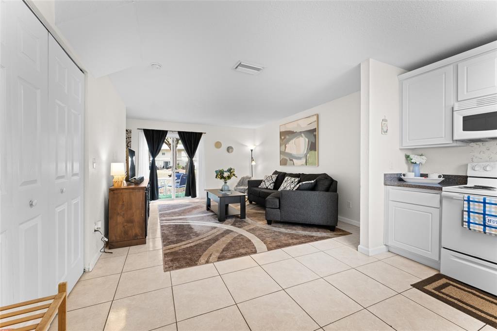 An open-concept living room with tile floors, a dark sofa, and sliding glass patio doors — 4420 CARTER ROAD UNIT 47, ST AUGUSTINE, FL