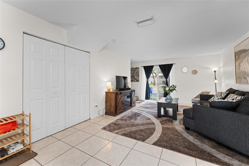 A living room with tile floors, a dark sofa, a rug, and a sliding glass door — 4420 CARTER ROAD UNIT 47, ST AUGUSTINE, FL
