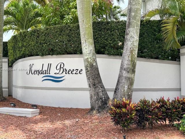 A curved white wall displays the Kendall Breeze community sign beneath palm trees and hedges — 12444 SW 125th St, Miami FL 33186, MIAMI, FL