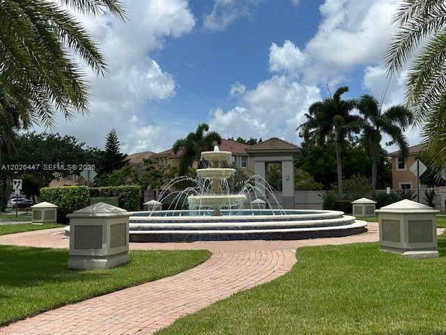 A tiered stone fountain sits in the center of a landscaped courtyard with palm trees — 12444 SW 125th St, Miami FL 33186, MIAMI, FL
