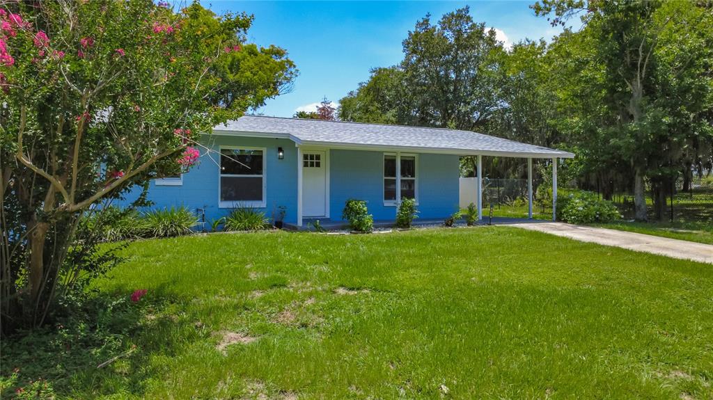 A single-story blue house with a white door and a covered carport sits on grass — 460 N PINE AVENUE, OVIEDO, FL