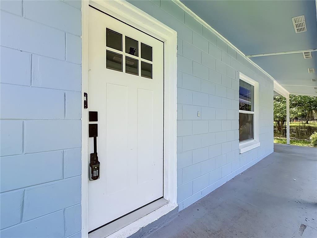A white front door with a keypad lock is set in a light blue block wall — 460 N PINE AVENUE, OVIEDO, FL