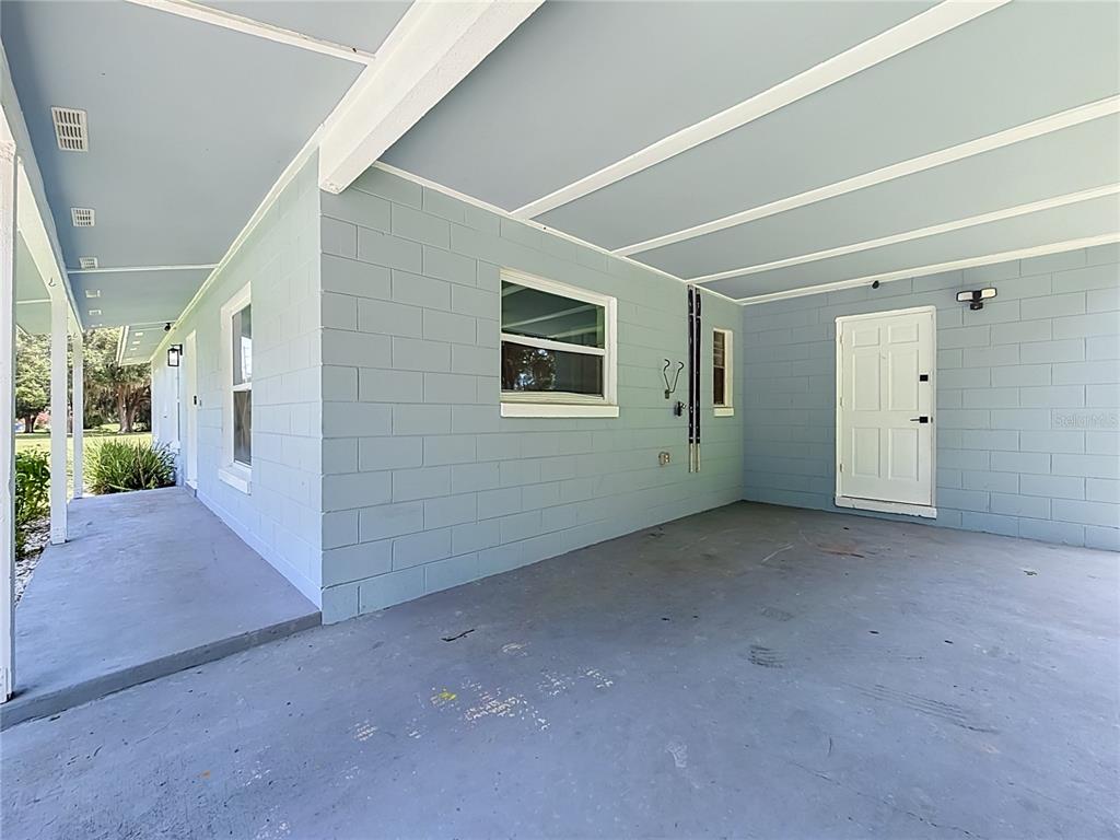 A light blue painted concrete block carport with a white door and a side walkway — 460 N PINE AVENUE, OVIEDO, FL