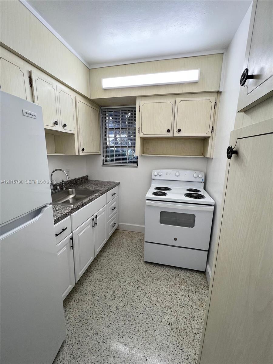 A small galley kitchen features white cabinets, a white stove, and a speckled floor — 675 SW 7th Ave # 2, Miami FL 33130, MIAMI, FL