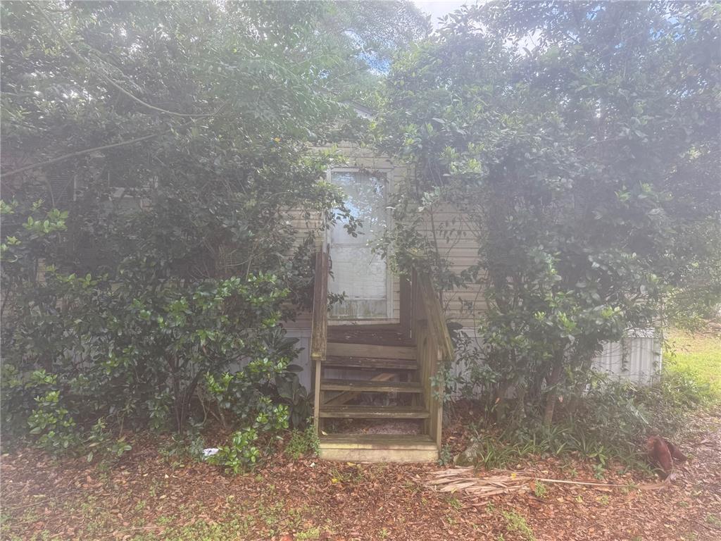 A wooden staircase leads to the front door of a mobile home surrounded by trees — 14935 SE 47TH COURT, SUMMERFIELD, FL