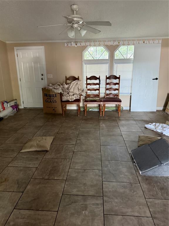 A room with tiled floors, a ceiling fan, two wooden chairs, and a cardboard box — 14935 SE 47TH COURT, SUMMERFIELD, FL