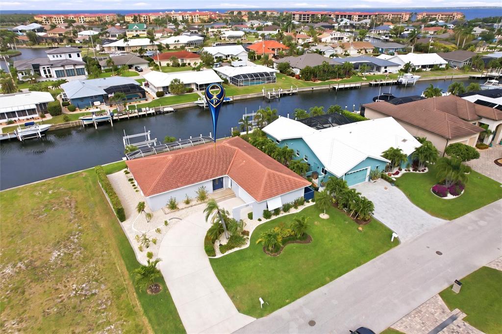 An aerial view shows a waterfront house with a red tile roof and a boat dock — 79 TROPICANA DRIVE, PUNTA GORDA, FL