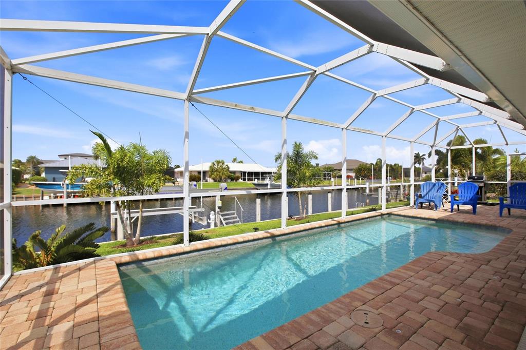 A screened-in pool patio overlooks a canal with a boat dock and neighboring houses — 79 TROPICANA DRIVE, PUNTA GORDA, FL