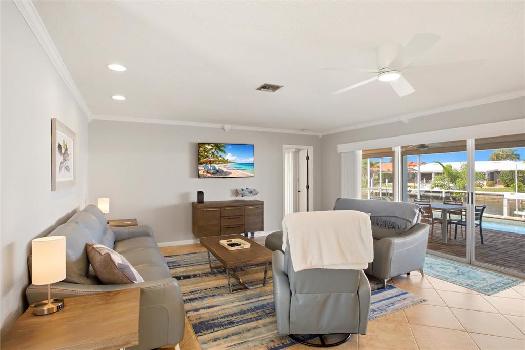 A living room features gray leather furniture, a television, and sliding doors opening to a pool — 79 TROPICANA DRIVE, PUNTA GORDA, FL