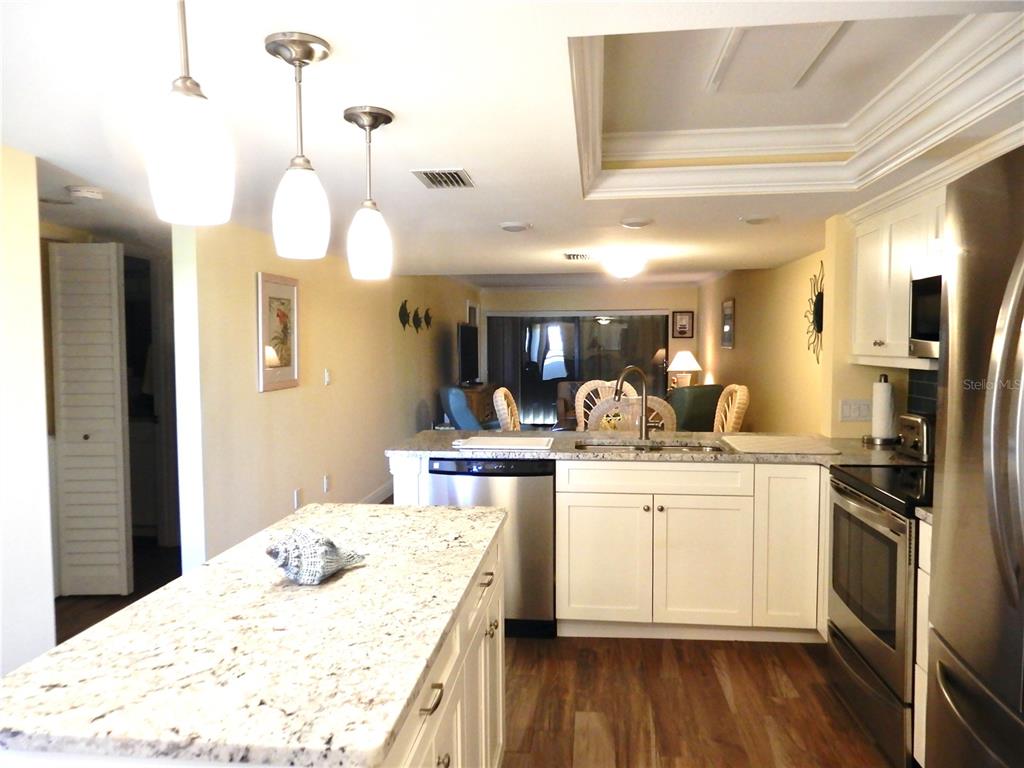 A kitchen with white cabinets, granite countertops, stainless steel appliances, and a central island — 103 1ST STREET E UNIT 210, TIERRA VERDE, FL