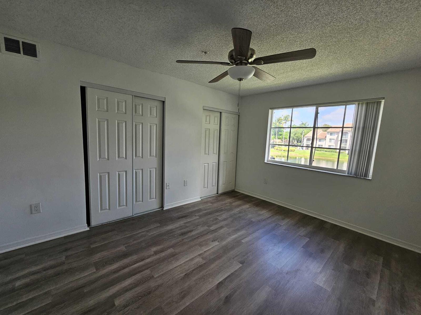 An empty bedroom features wood-look flooring, two sets of closet doors, and a ceiling fan — 12154 St.andrews Place # 206, Miramar FL 33025, MIRAMAR, FL