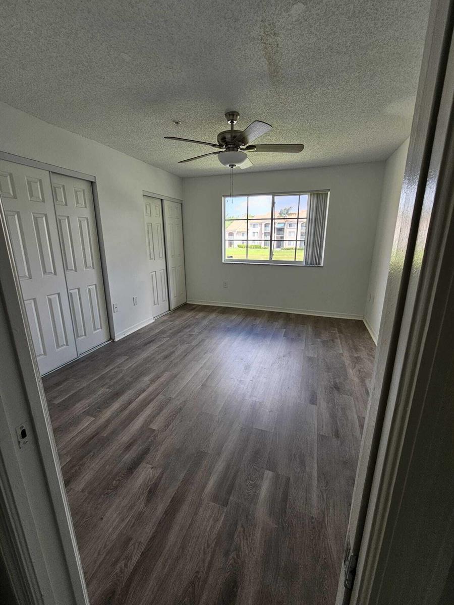 An empty bedroom features wood-look flooring, a ceiling fan, and two sets of closet doors — 12154 St.andrews Place # 206, Miramar FL 33025, MIRAMAR, FL