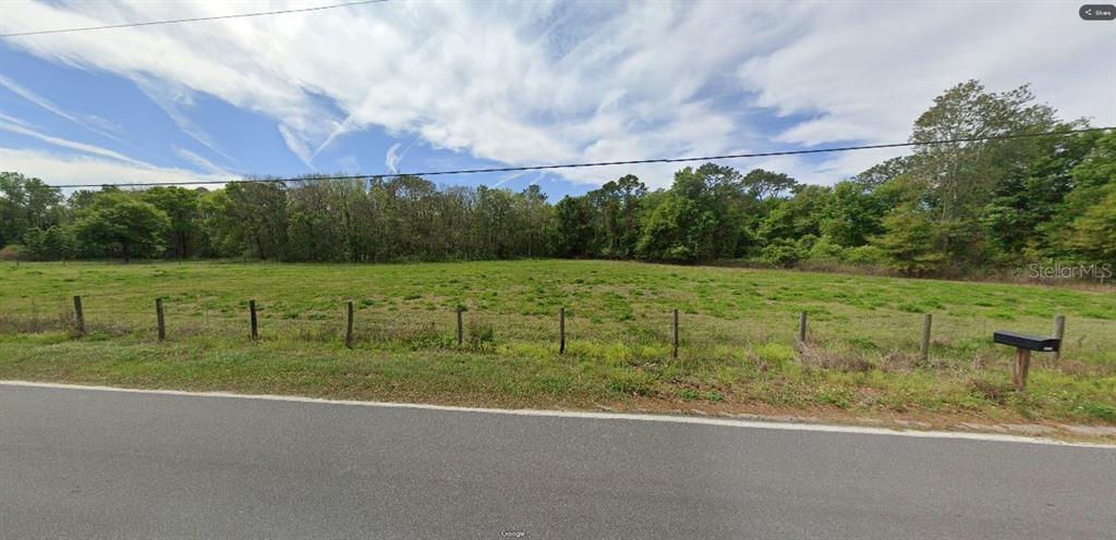 A flat, grassy vacant lot is enclosed by a wire fence along a paved road — GREEN POND RD, POLK CITY, FL
