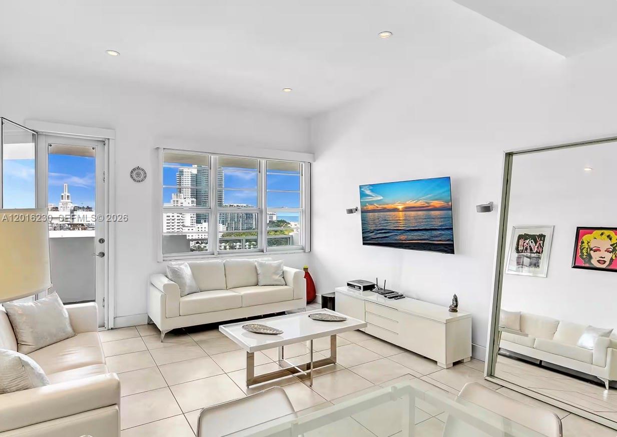 A bright living room features white furniture, a large wall-mounted television, and floor-to-ceiling windows — 100 Lincoln Rd # 1641, Miami Beach FL 33139, MIAMI BEACH, FL