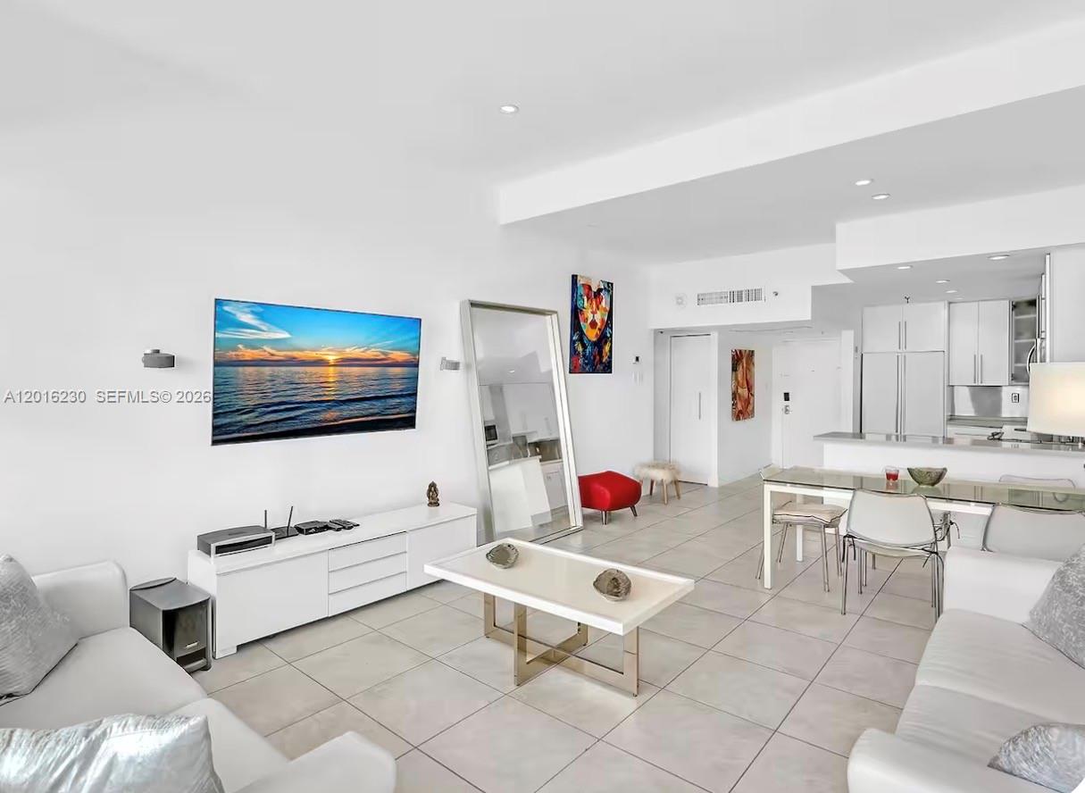 A bright living room features white furniture, a wall-mounted television, and tile flooring — 100 Lincoln Rd # 1641, Miami Beach FL 33139, MIAMI BEACH, FL