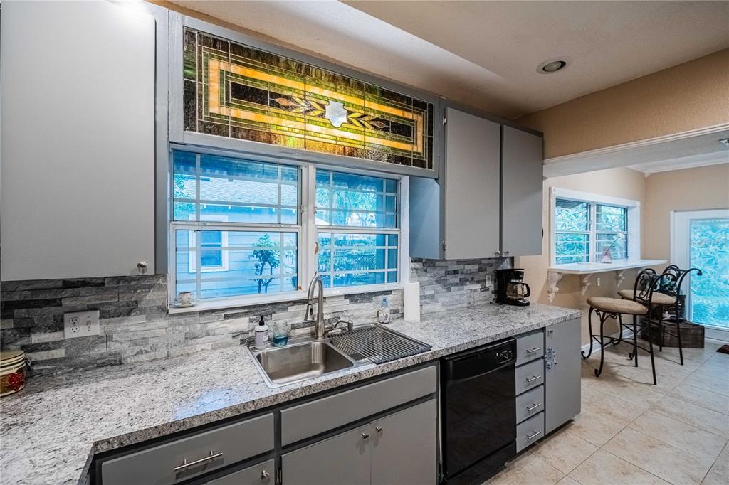 A kitchen features gray cabinets, granite countertops, a stone backsplash, and a stained glass window — 828 OSCEOLA STREET, LAKELAND, FL