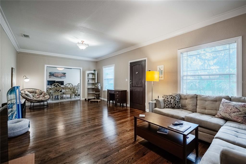 A living room with hardwood floors, a beige sectional sofa, and an adjacent dining area — 828 OSCEOLA STREET, LAKELAND, FL