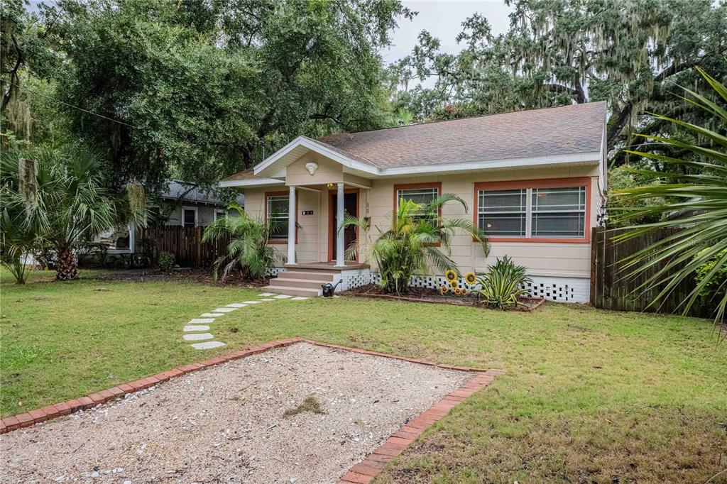 A single-story house with beige siding, a front porch, and a gravel driveway — 828 OSCEOLA STREET, LAKELAND, FL