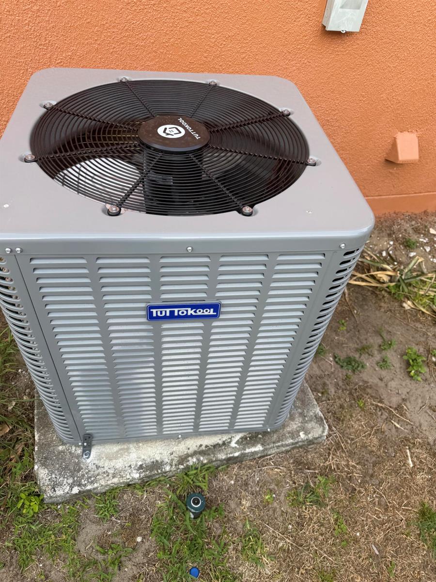 A gray TuttoKool air conditioning condenser unit sits on a concrete pad outside a building — 133 Inconnu Court, FL 34759, FL