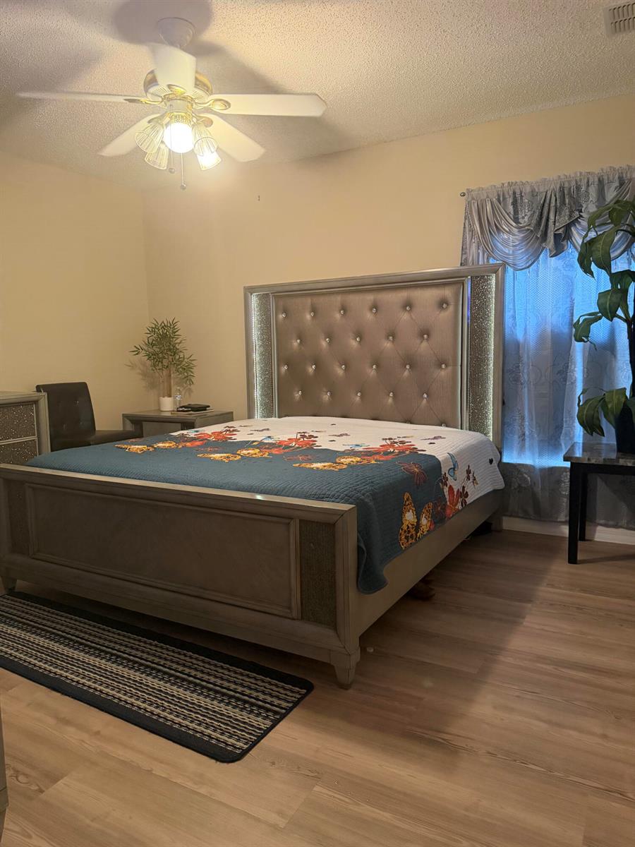 A bedroom features a tufted, illuminated headboard, a butterfly-patterned quilt, and light wood flooring — 133 Inconnu Court, FL 34759, FL