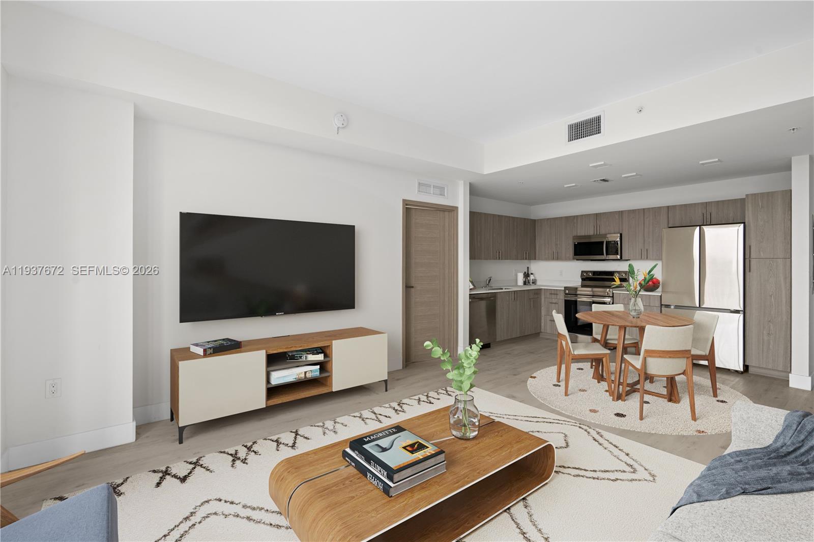 A modern living room and kitchen area features light wood flooring and neutral-toned cabinetry — 1601 SW 32 Avenue # 313, Miami FL 33145, MIAMI, FL
