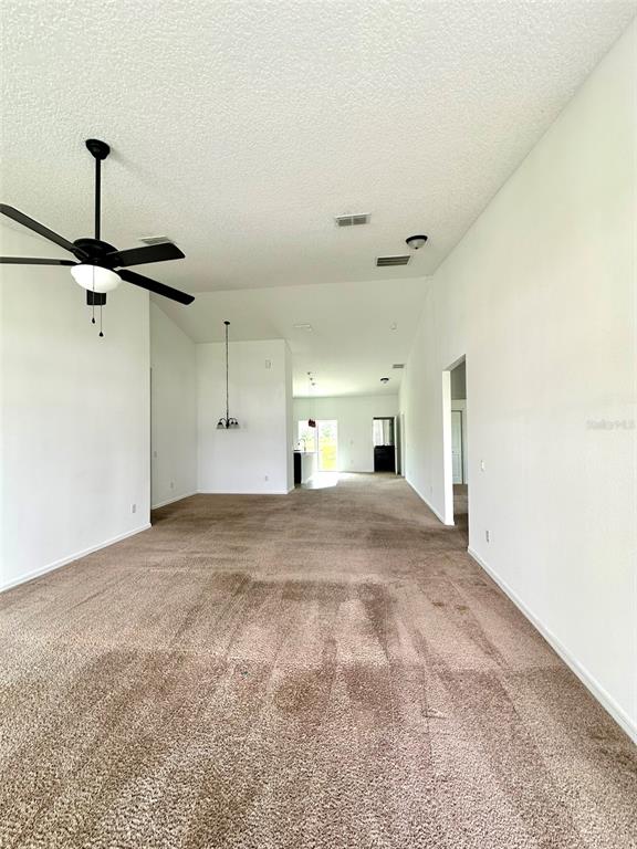 A spacious room with beige carpeting, white walls, a ceiling fan, and recessed lighting — 102 AURELIA COURT, KISSIMMEE, FL