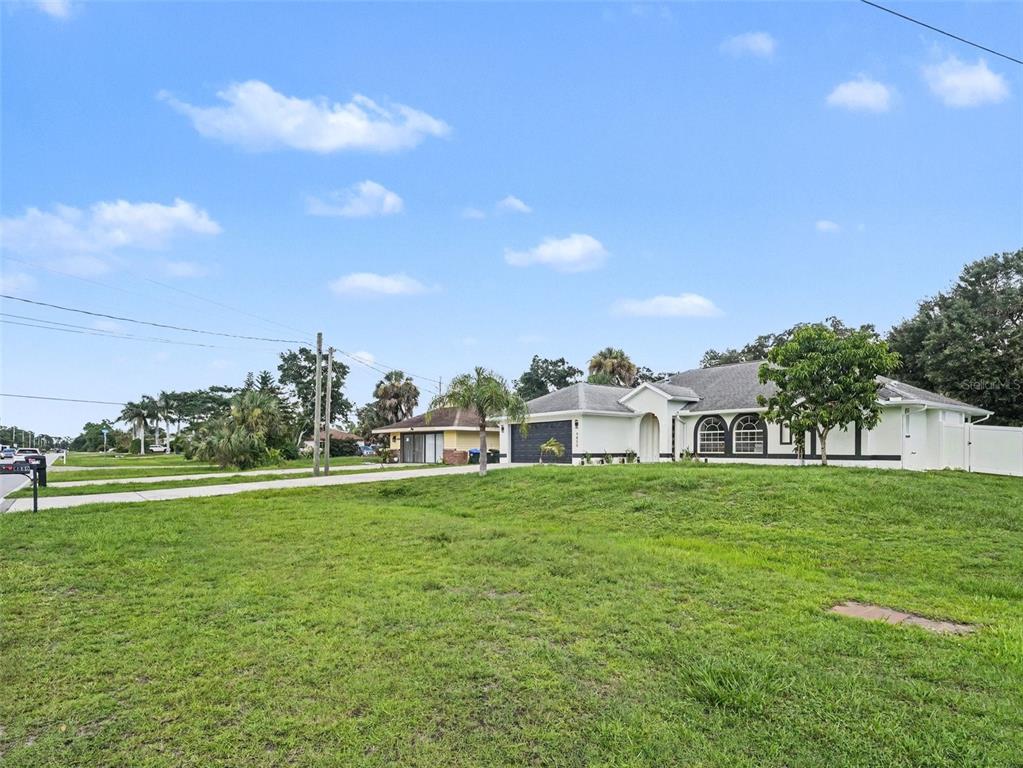 A single-story house with a white exterior, dark garage door, and a large grassy yard — 4850 S SALFORD BLVD, NORTH PORT, FL