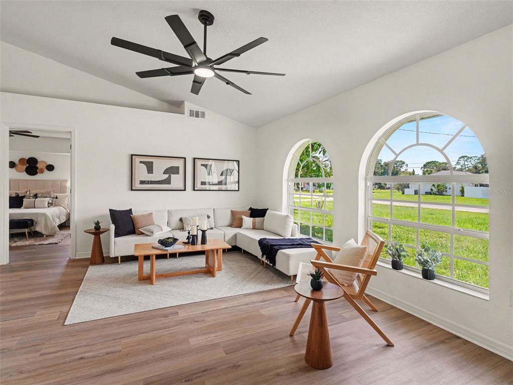 A living room features a white sectional sofa, wood coffee table, and arched windows — 4850 S SALFORD BLVD, NORTH PORT, FL