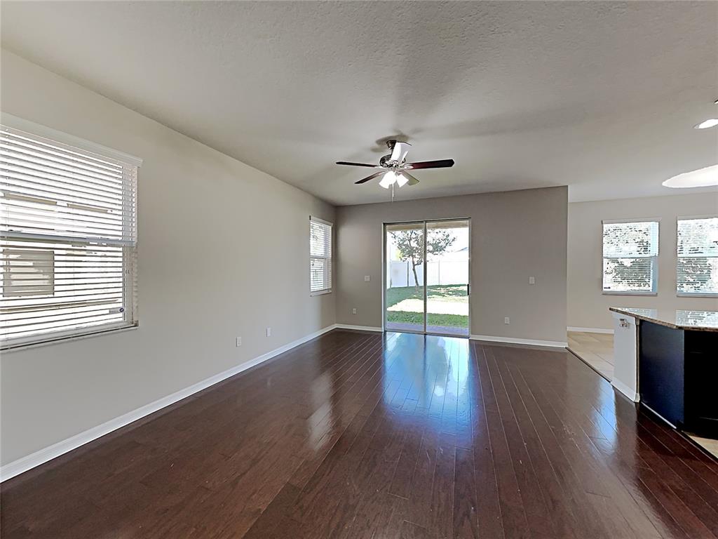 A living room with dark wood flooring, a ceiling fan, and sliding glass patio doors — 7226 LUMBER PORT DRIVE, RUSKIN, FL