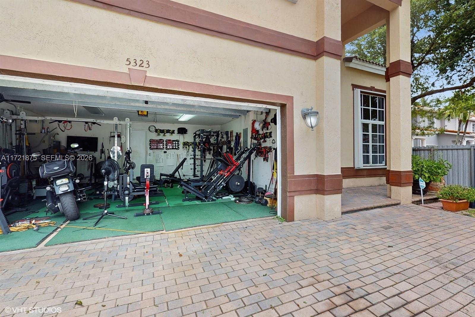 A residential garage converted into a home gym with exercise equipment and a motorcycle — 5323 NW 109th Ct, Doral FL 33178, DORAL, FL