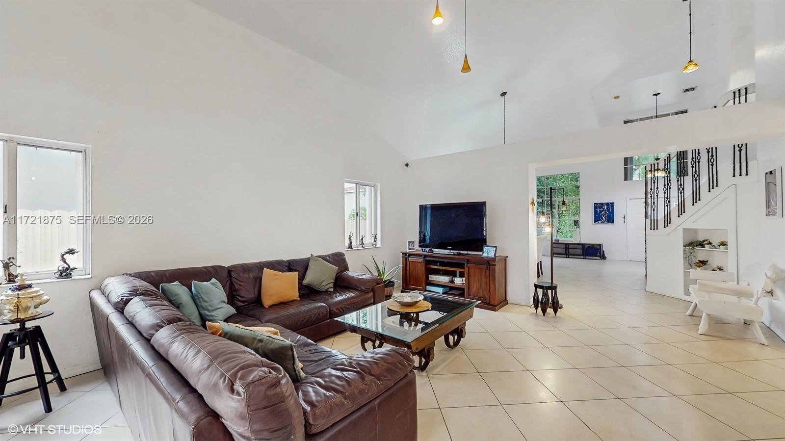 A living room features a brown leather sectional, a glass coffee table, and tile flooring — 5323 NW 109th Ct, Doral FL 33178, DORAL, FL