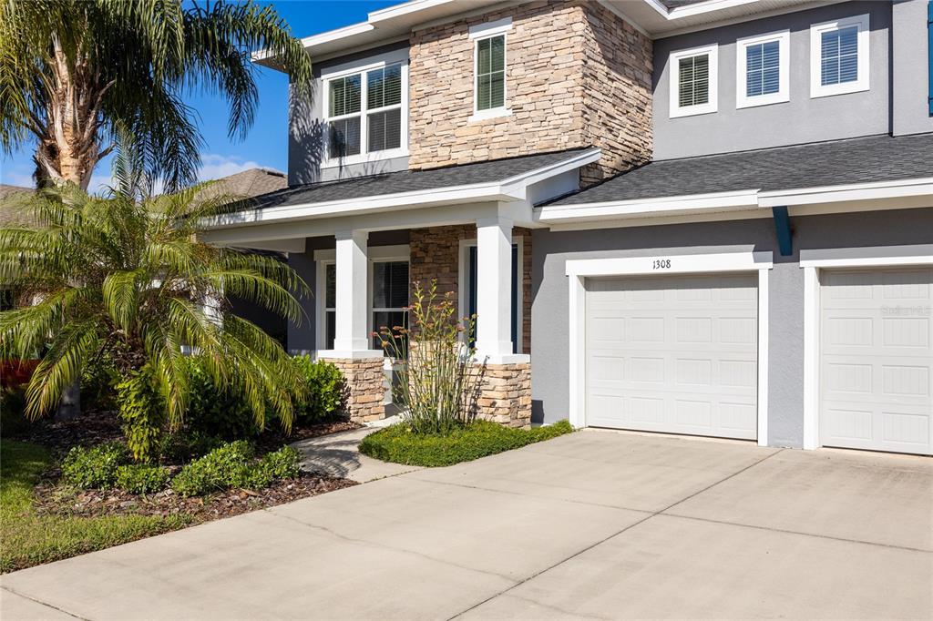 A two-story house exterior features a stone facade, gray siding, and a two-car garage — 1308 CHARLEEN STREET, BRANDON, FL