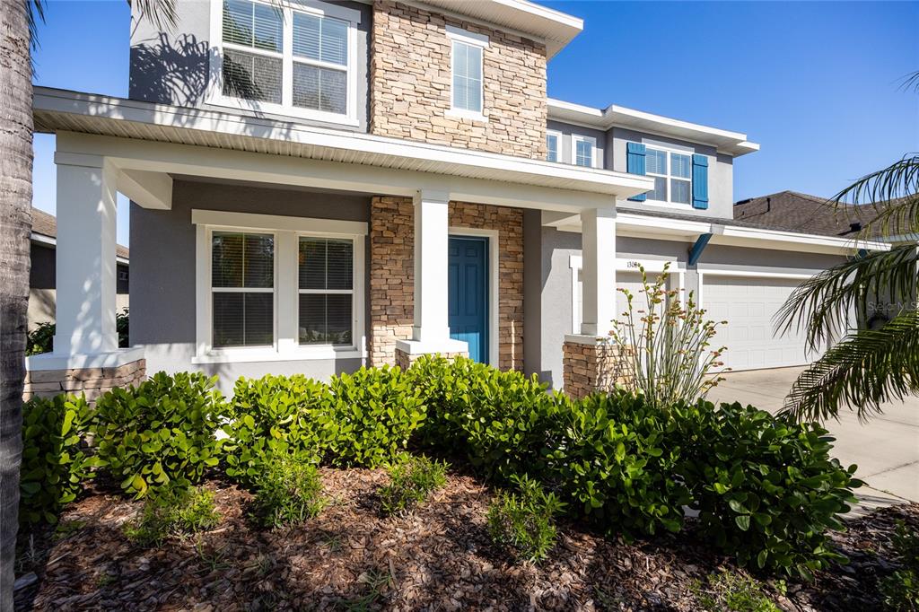 A two-story house exterior features a stone facade, a blue front door, and landscaping — 1308 CHARLEEN STREET, BRANDON, FL