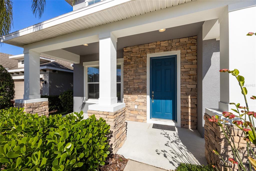 A covered front porch features a blue door, stone veneer accents, and white columns — 1308 CHARLEEN STREET, BRANDON, FL