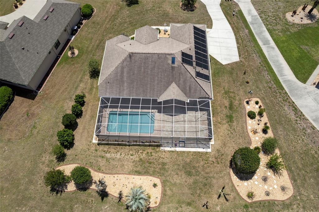 An aerial view shows a house with a screened-in pool and solar panels on the roof — 1231 E WHIRL AWAY CIRCLE, INVERNESS, FL