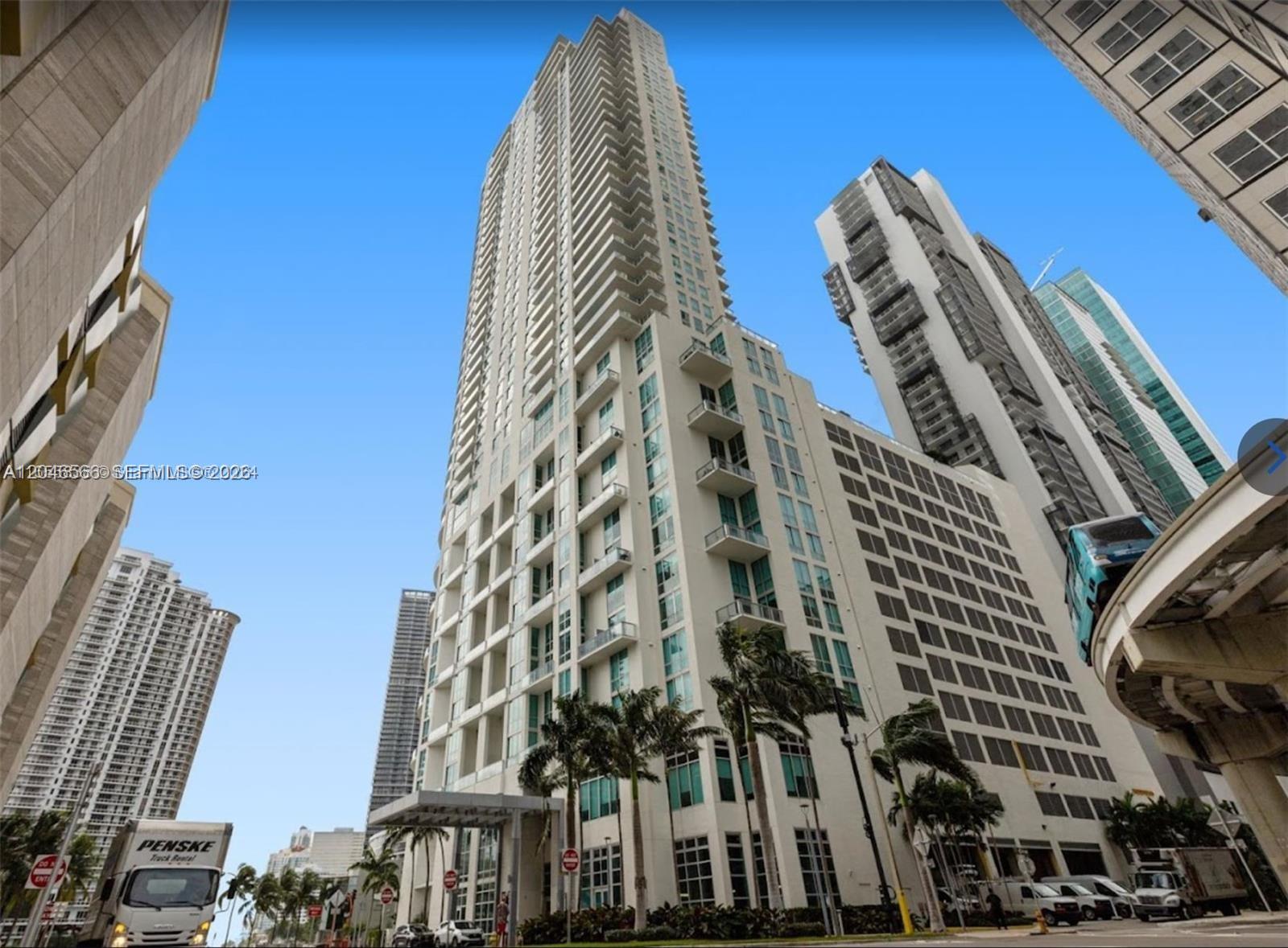A low-angle view of a tall, modern residential skyscraper with balconies and a parking garage — 300 S Biscayne Blvd # 2603, Miami FL 33131, MIAMI, FL