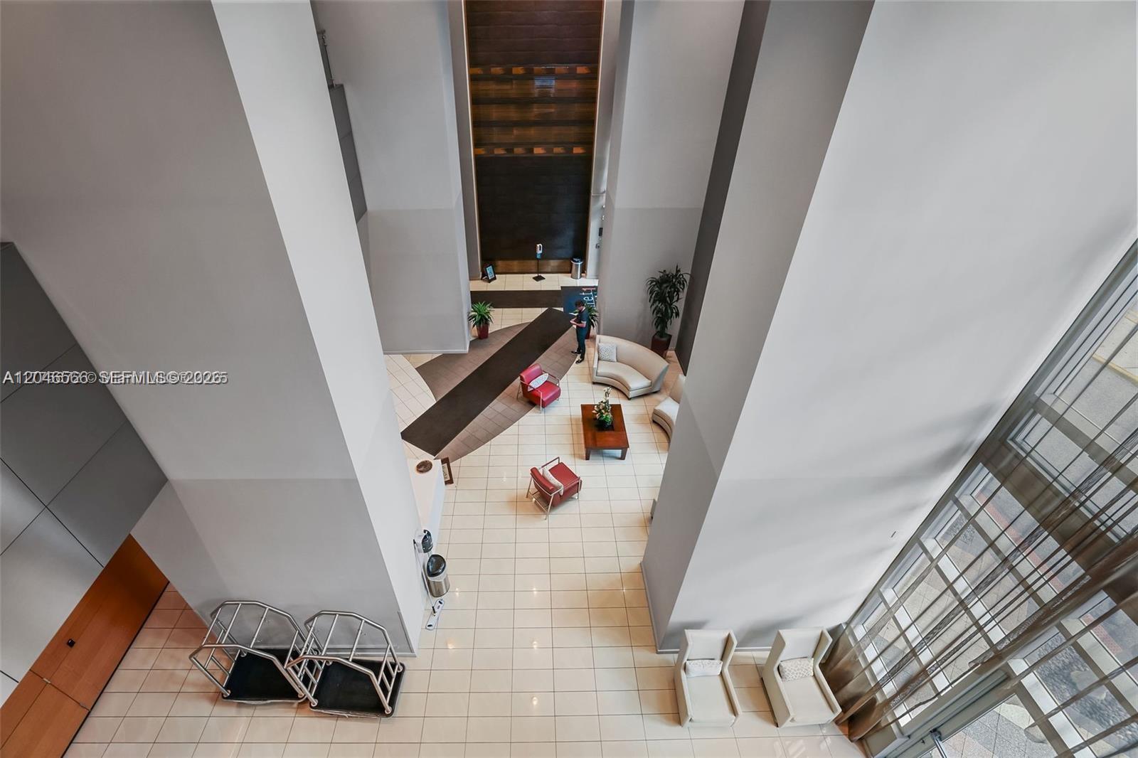 A high-angle view shows a modern lobby with tile floors, seating areas, and tall columns — 300 S Biscayne Blvd # 2603, Miami FL 33131, MIAMI, FL