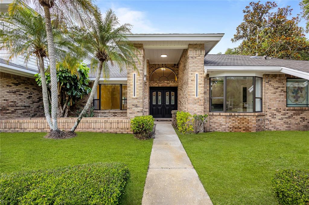 A brick house exterior features a central entryway with double doors and a concrete walkway — 2901 ST ANDREWS BOULEVARD, TARPON SPRINGS, FL