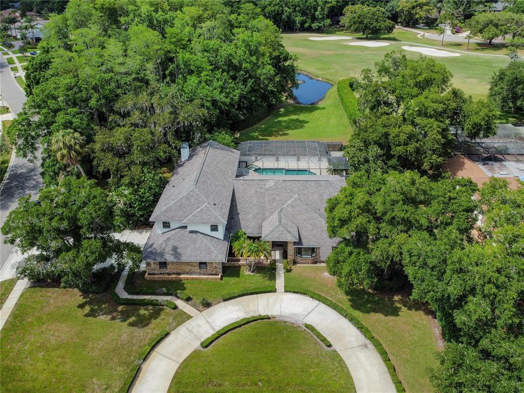 An aerial view shows a house with a pool enclosure, circular driveway, and surrounding trees — 2901 ST ANDREWS BOULEVARD, TARPON SPRINGS, FL