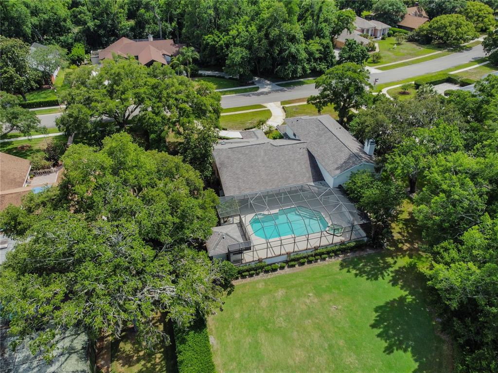 An aerial view shows a house with a screened-in pool and a large grassy backyard — 2901 ST ANDREWS BOULEVARD, TARPON SPRINGS, FL