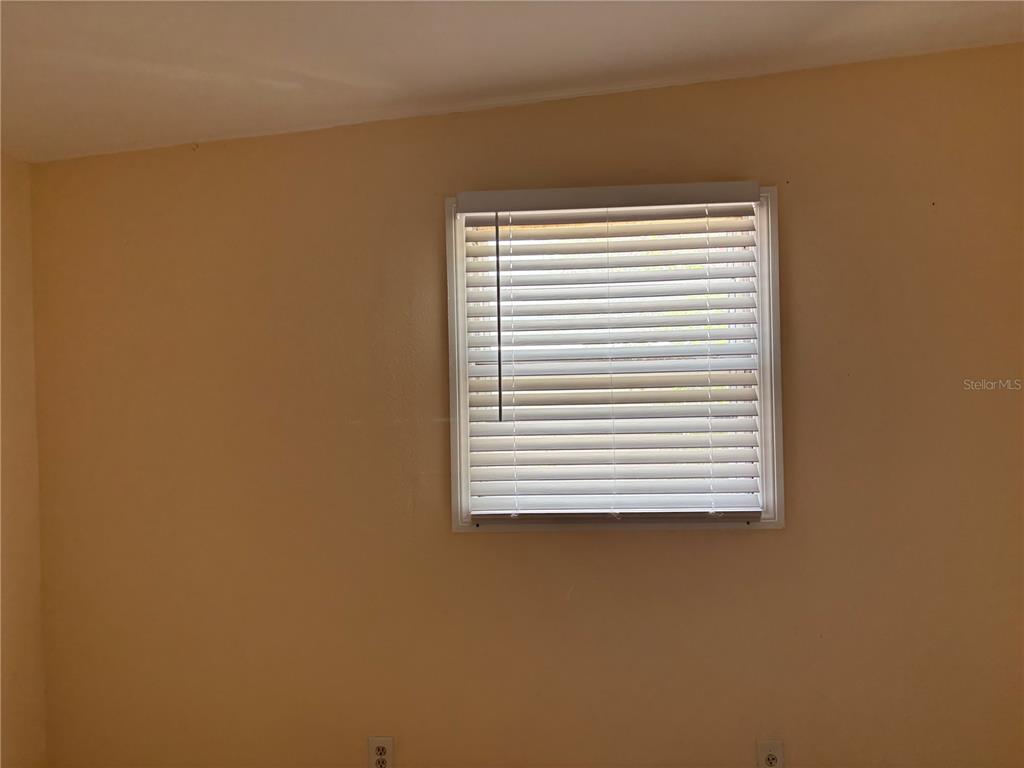 A room with beige walls, a window with white blinds, and two electrical outlets — 1320 LARSEN LN, TAMPA, FL