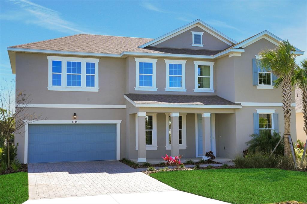 A two-story suburban house with a blue garage door, beige siding, and a paved driveway — 7445 SEA MANATEE STREET, PARRISH, FL