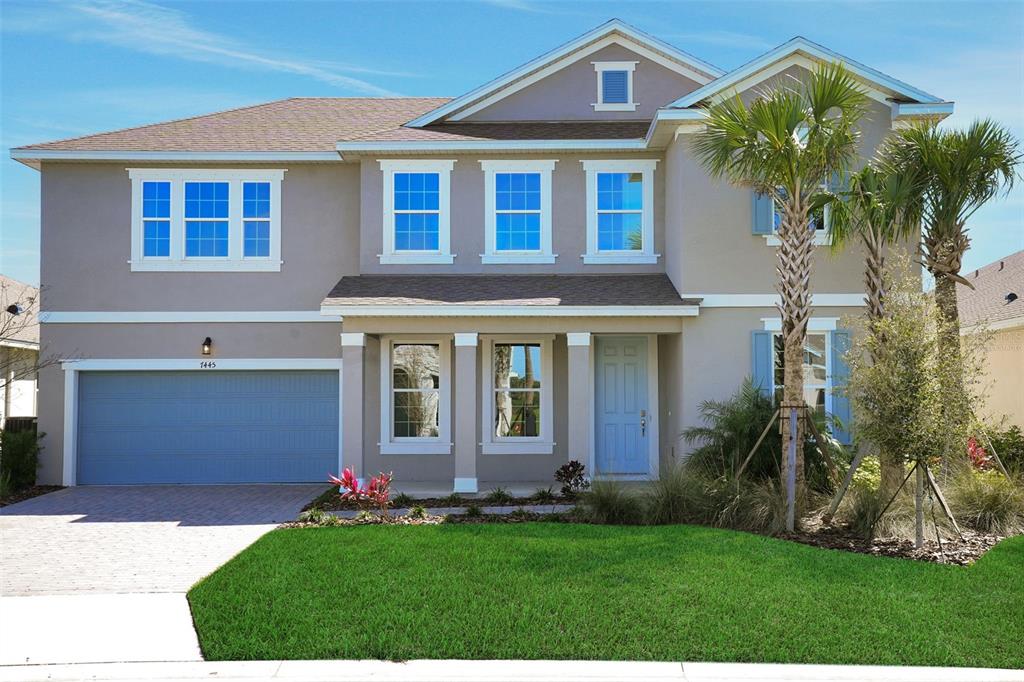 A two-story suburban house with a light brown exterior, blue garage door, and front lawn — 7445 SEA MANATEE STREET, PARRISH, FL