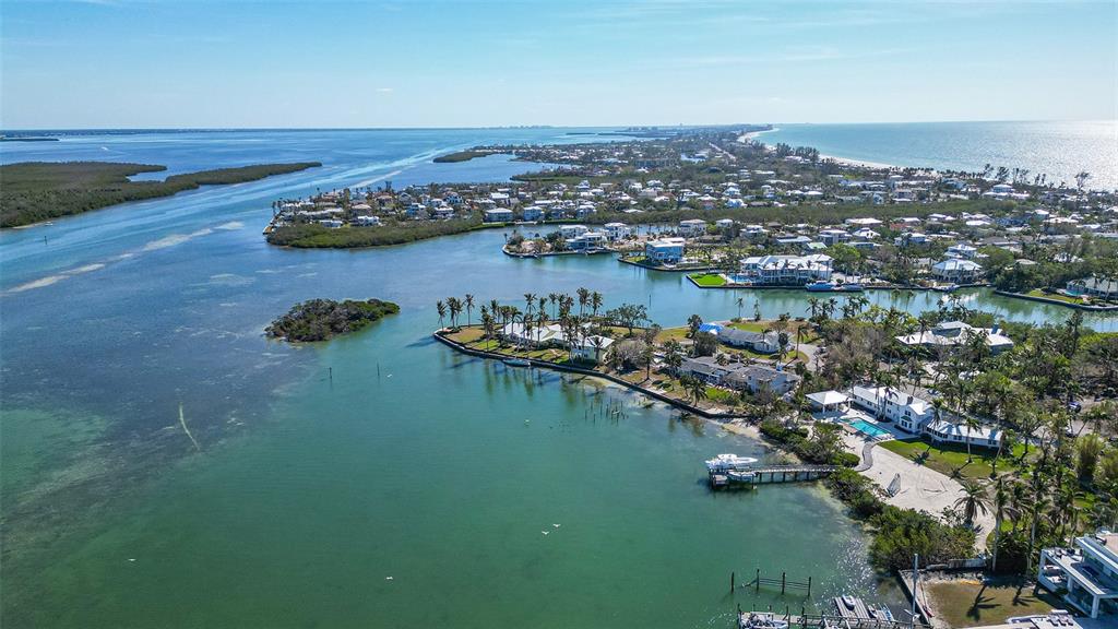 An aerial view shows waterfront homes along a coastal inlet with docks and vegetation — 6516 BAYOU HAMMOCK ROAD, LONGBOAT KEY, FL