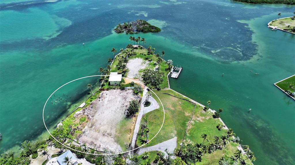An aerial view shows a cleared waterfront lot with a small house and palm trees — 6516 BAYOU HAMMOCK ROAD, LONGBOAT KEY, FL