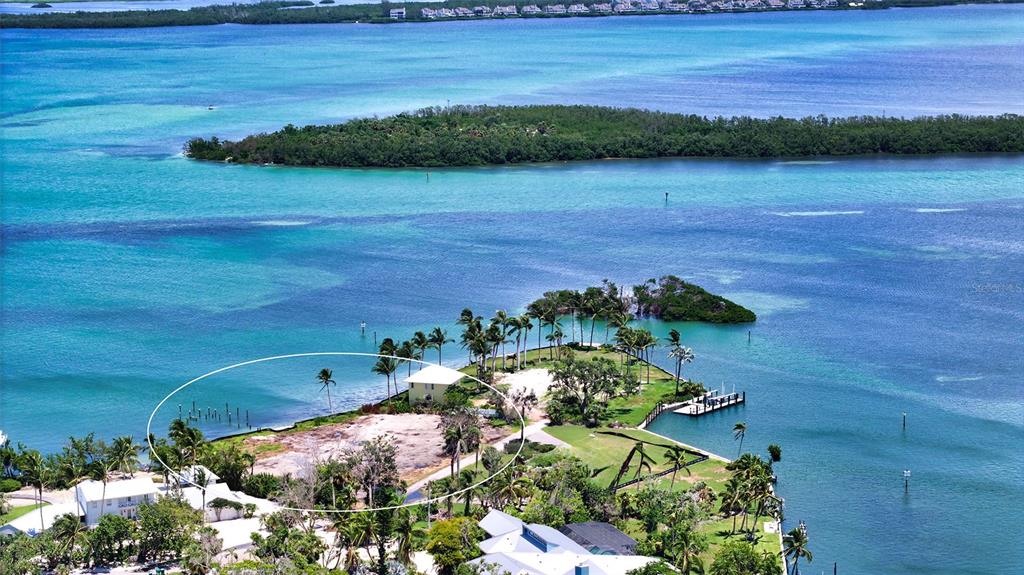 An aerial view shows a waterfront property with a house, palm trees, and a dock — 6516 BAYOU HAMMOCK ROAD, LONGBOAT KEY, FL