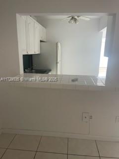 A kitchen with white cabinets is viewed through a tiled pass-through window from another room — 1441 Lincoln Rd # 414, Miami Beach FL 33139, MIAMI BEACH, FL