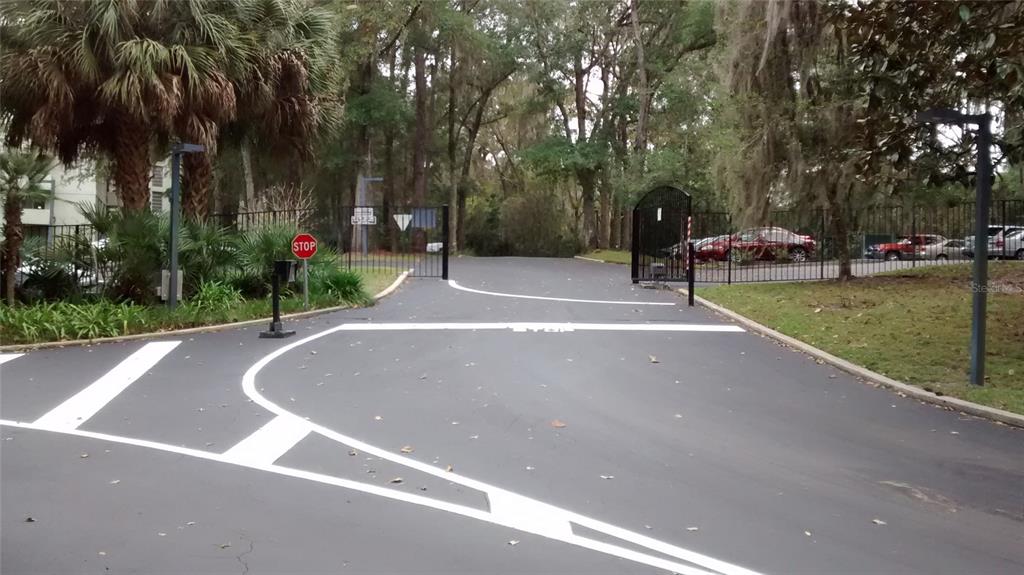 A paved driveway leads to a gated entrance surrounded by trees and landscaping — 1719 NW 23RD AVENUE UNIT 5A, GAINESVILLE, FL