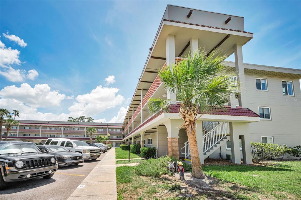 An exterior view of a multi-story apartment building with a parking lot and palm tree — 2072 AUSTRALIA WAY W UNIT 32, CLEARWATER, FL